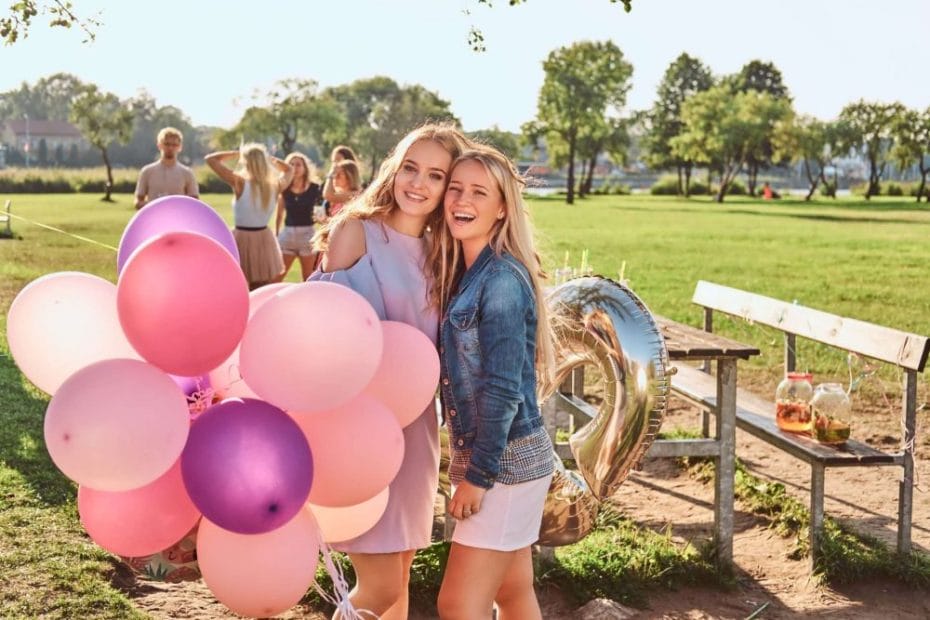 happy girlfriends posing with balloons near table celebrating birthday outdoor park scaled e1691622164452